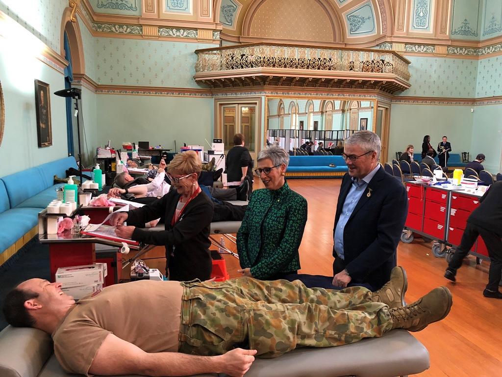 The Governor and Mr Howard speaking to an army officer giving blood in the Ballroom