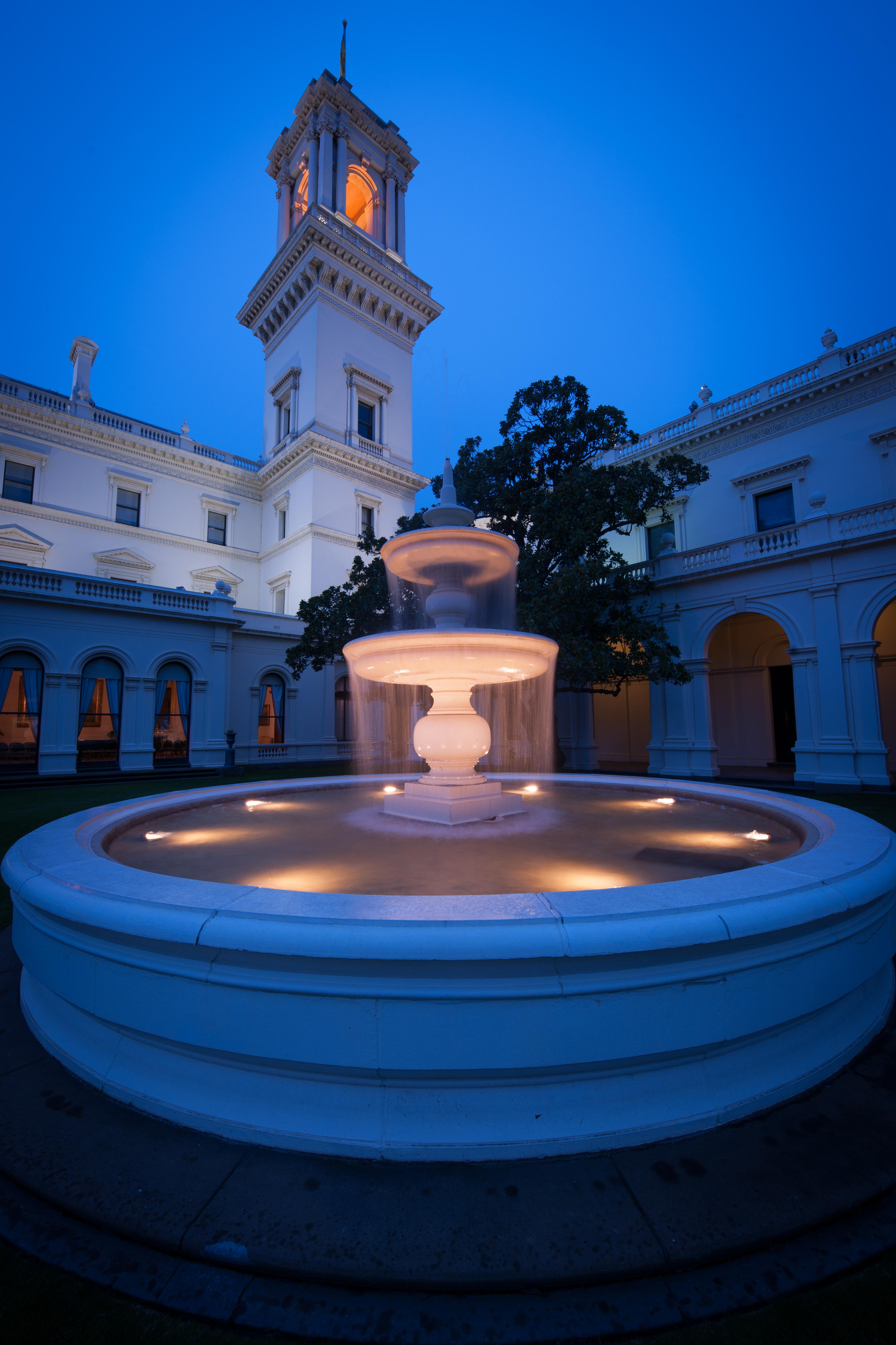 fountain at government house lit up at dusk.